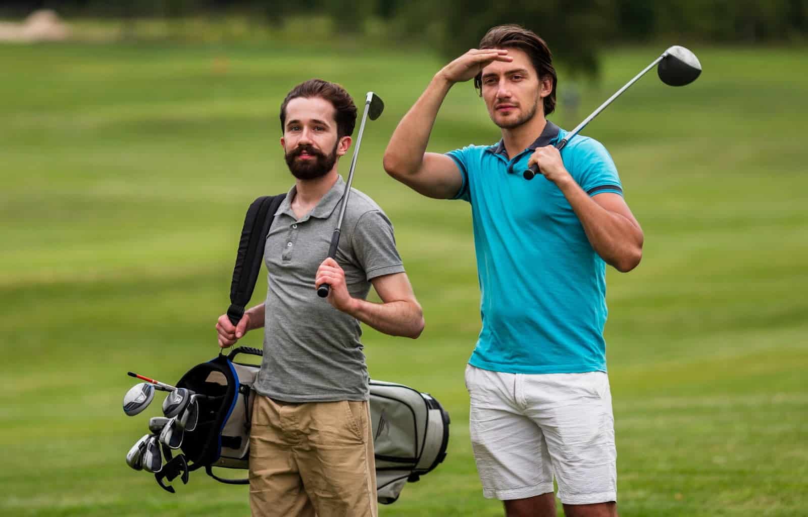 Two men standing on a golf course with clubs