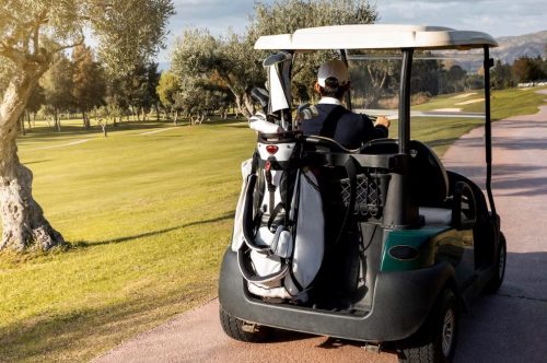 a man riding a golf cart with a golf bag