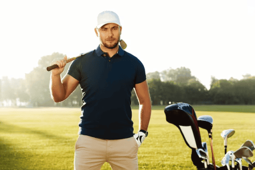 A male golfer stands on the field with a club