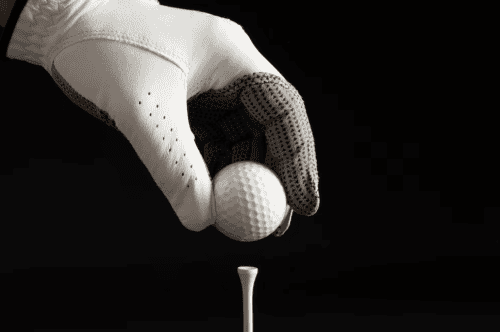 hand in gloves holds the golf ball on black background 