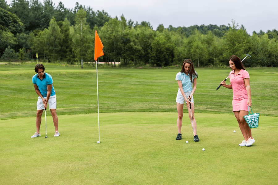 Three individuals engaged in a game of golf on a course, close to the target