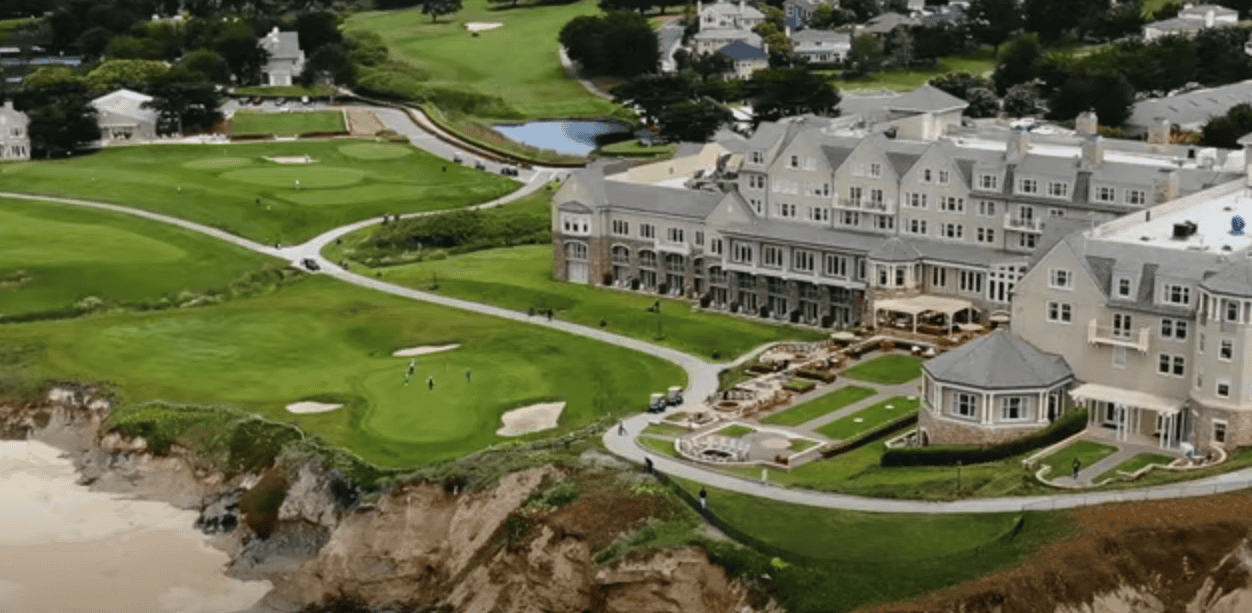 Aerial view of a golf course featuring white building beside it