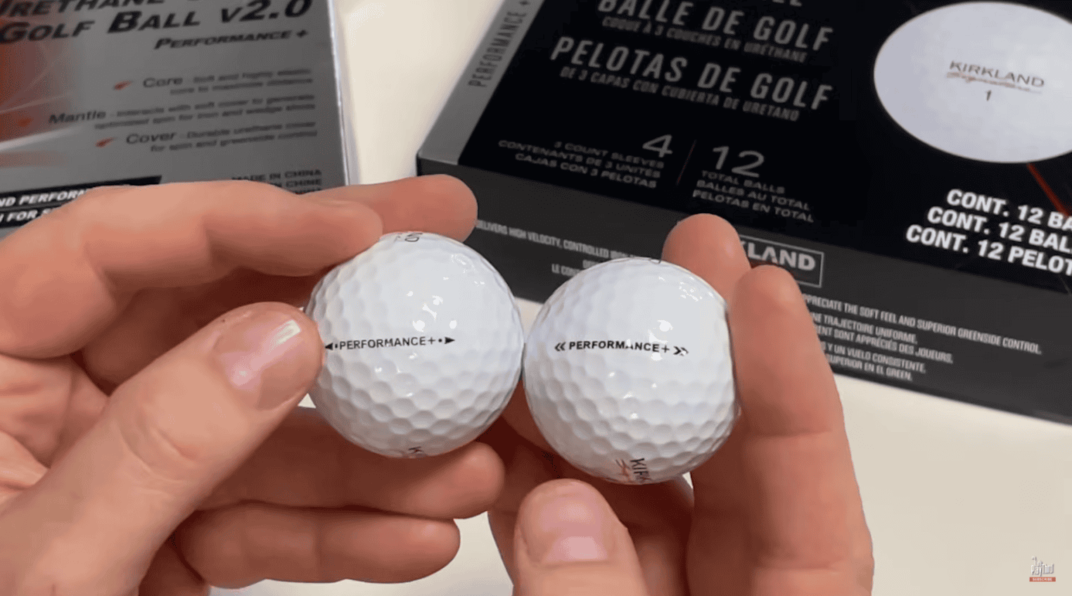 hand holding two golf balls with performance on it, two boxes behind
