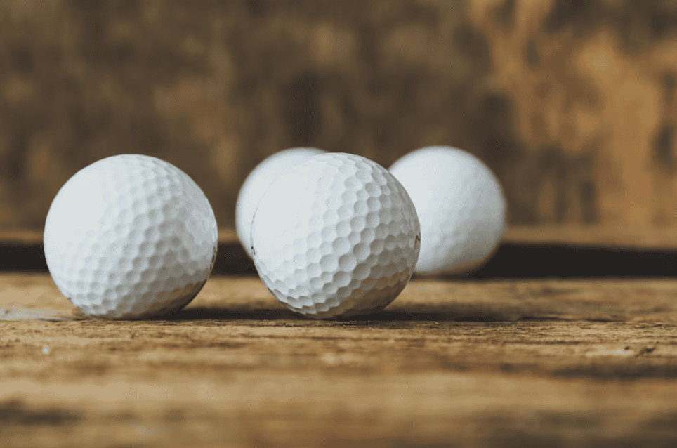 four gold balls on a wooden floor