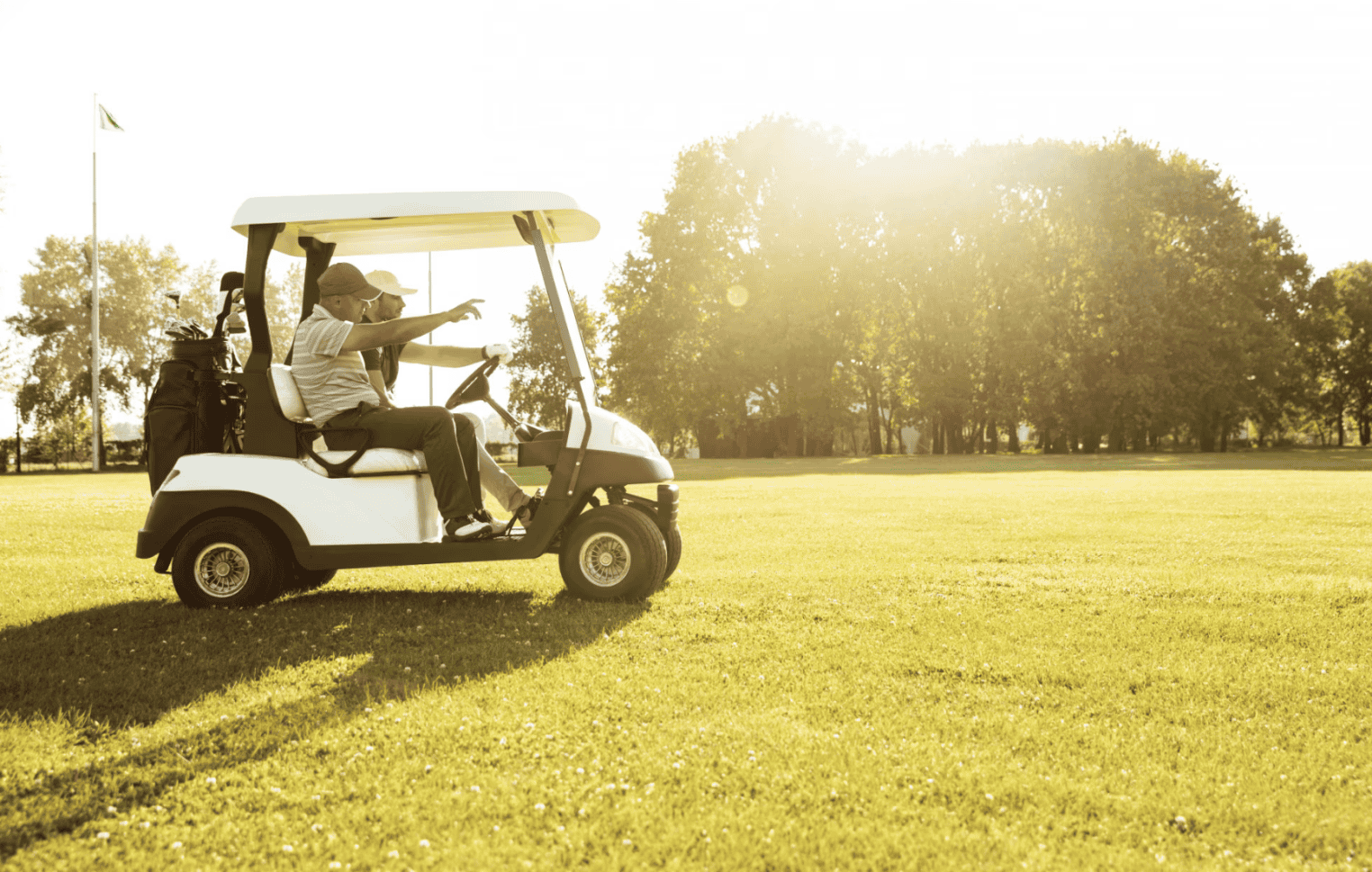 Two men driving a golf cart.